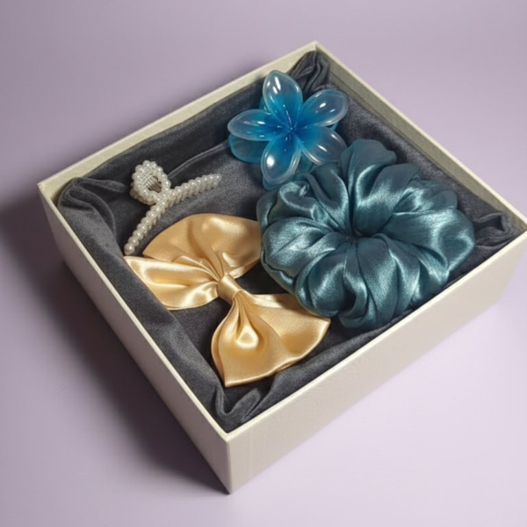 Set of gold and teal hair accessories in a box on a light purple background